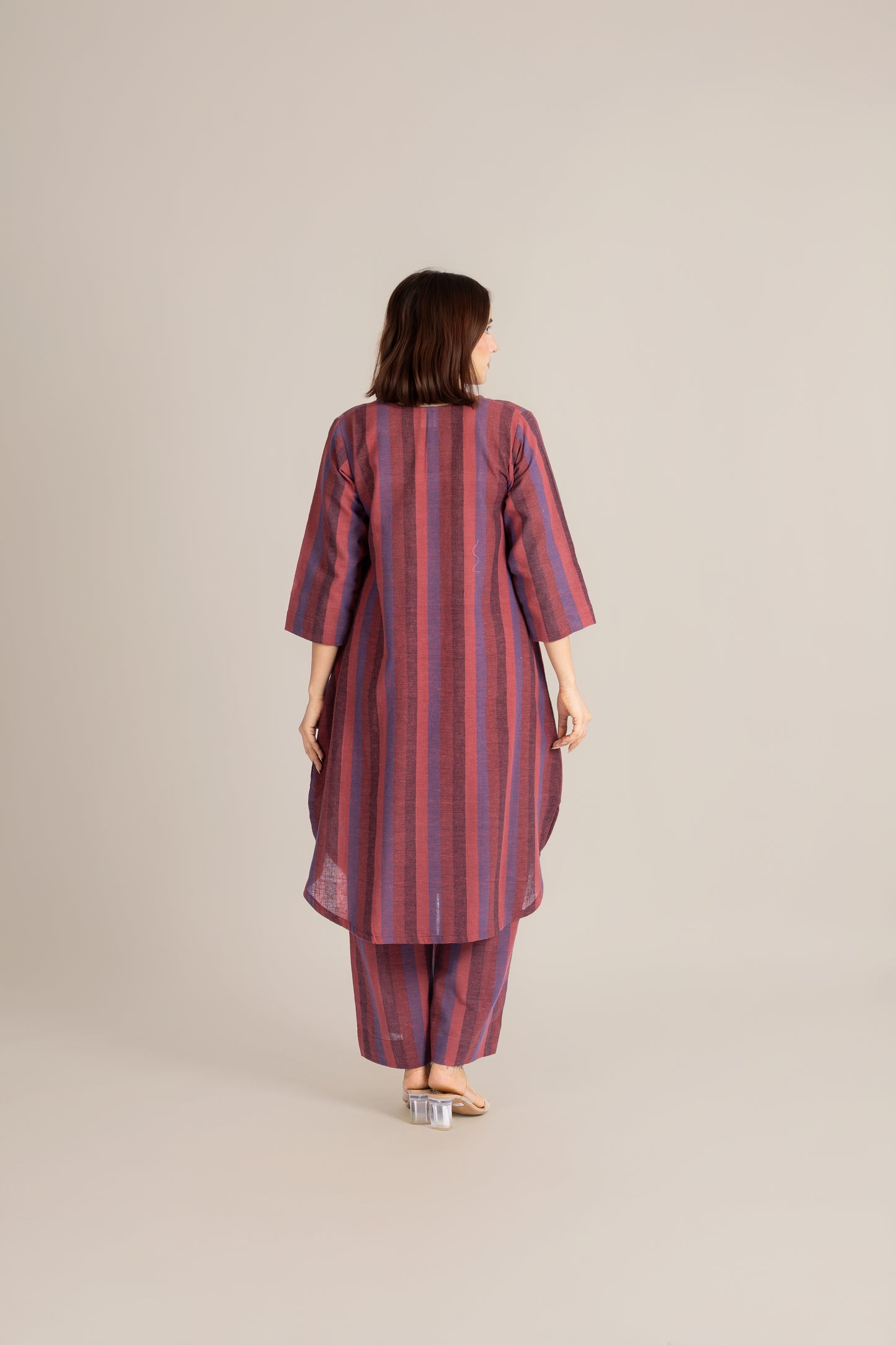 Woman wearing a red and purple striped outfit on a beige background