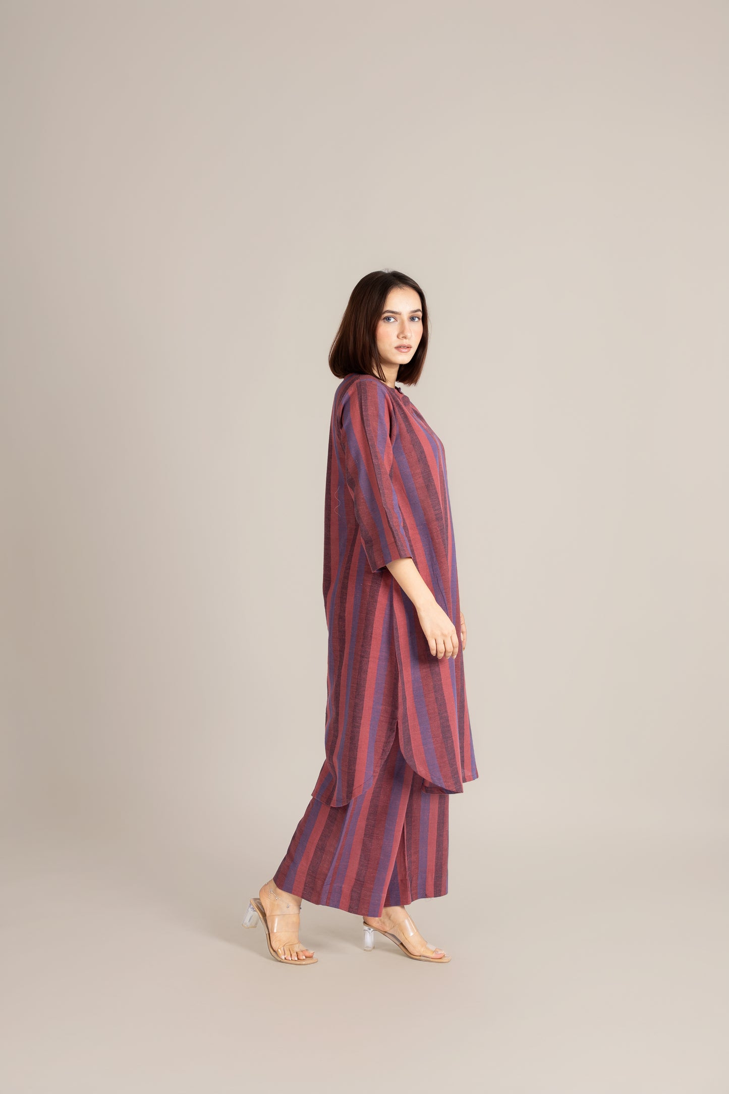 Woman wearing a striped dress standing against a plain background