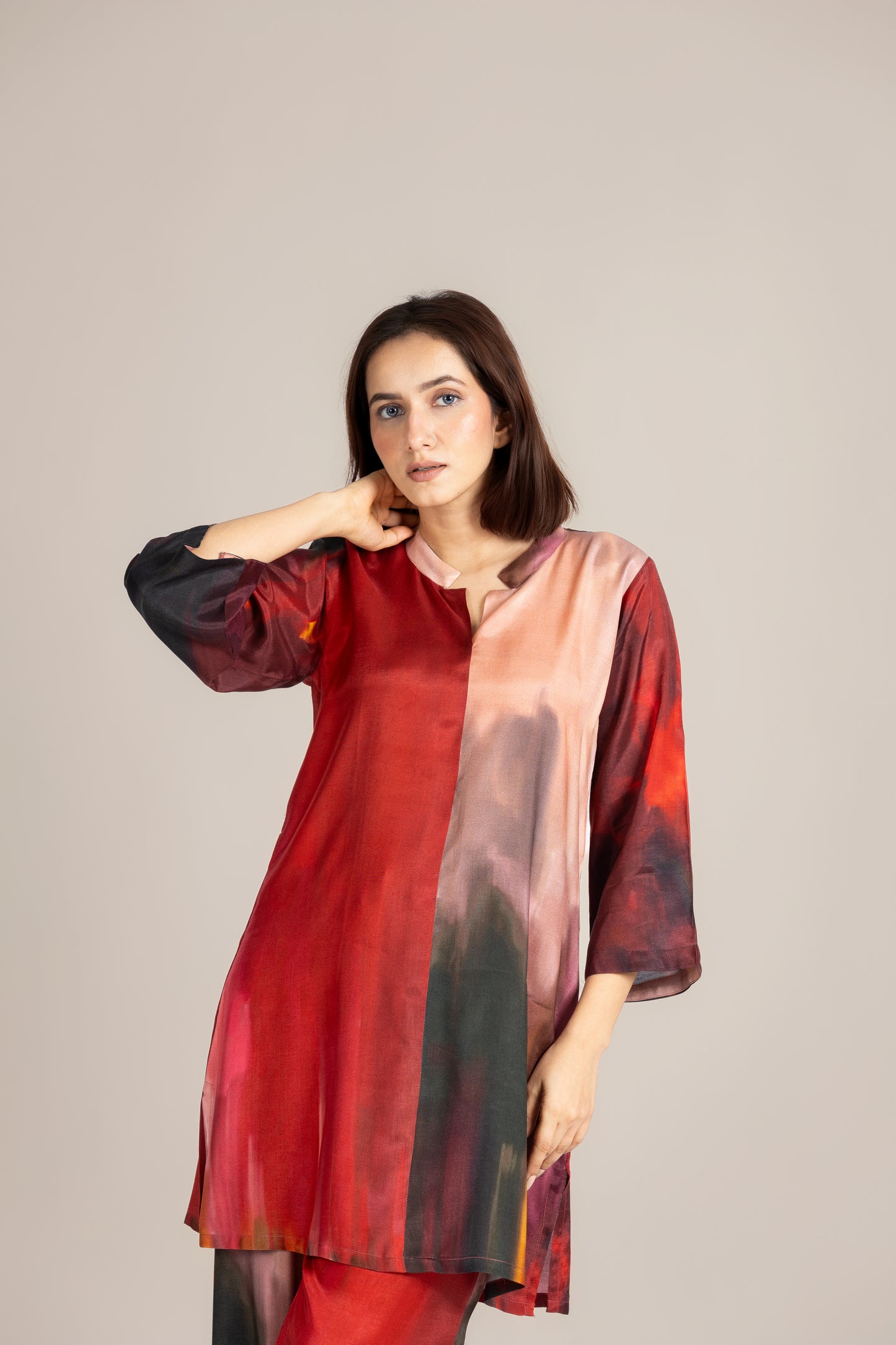 Woman wearing a red and black patterned kurta against a plain background