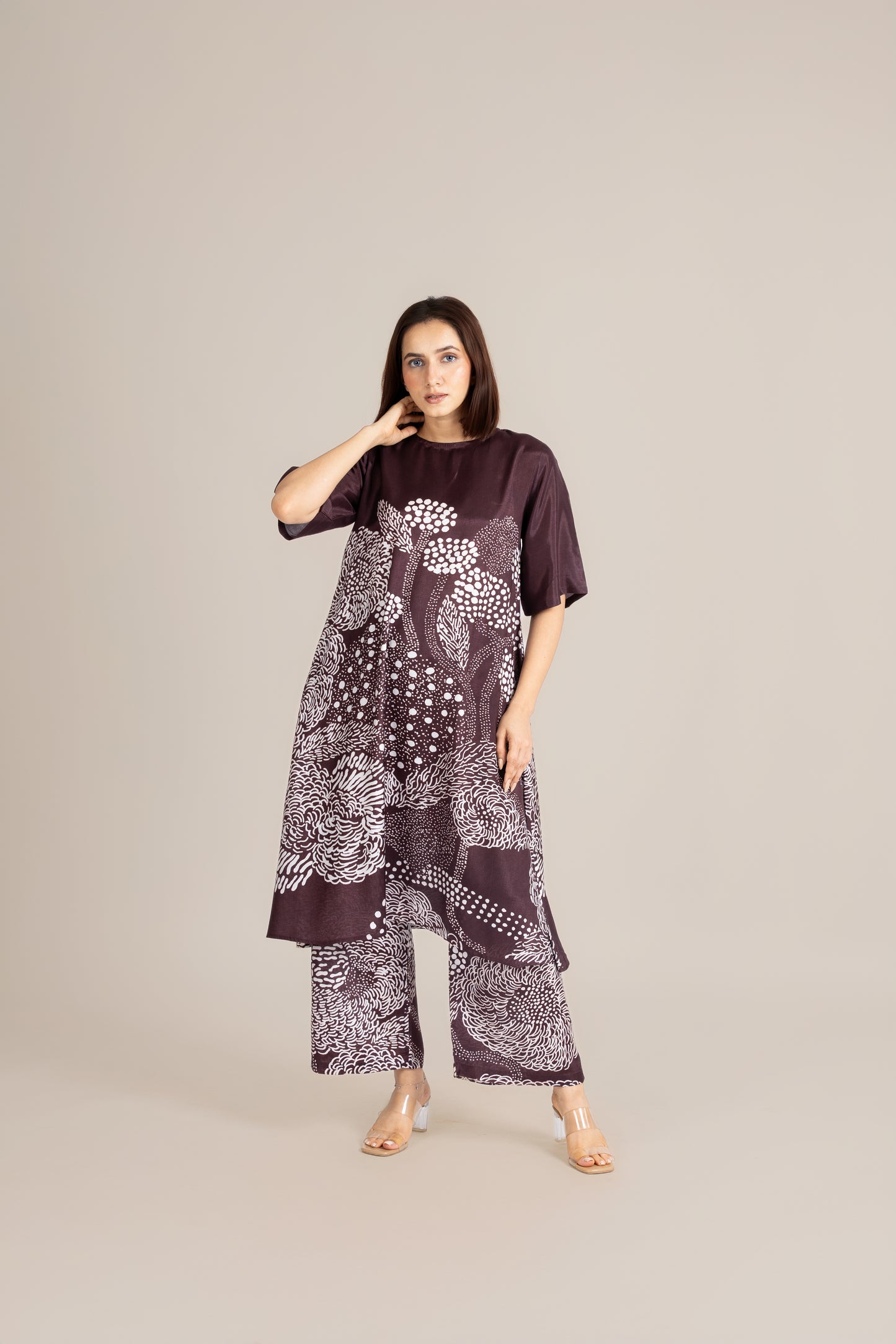 Woman wearing a dark purple outfit with white floral patterns on a beige background