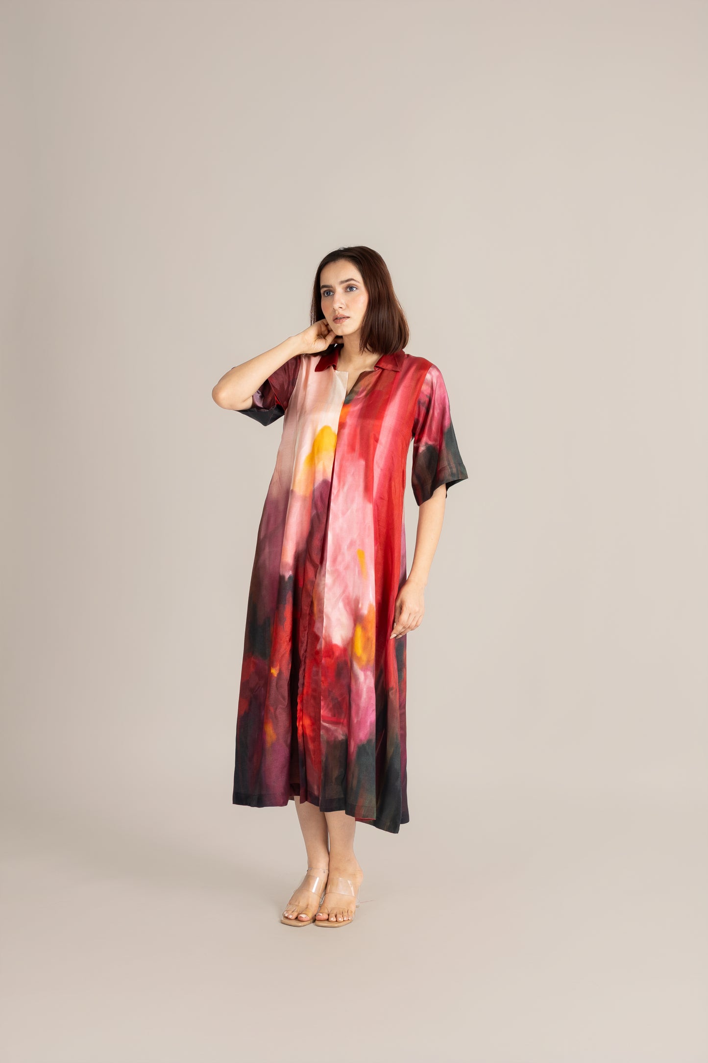 Woman wearing a colorful dress with abstract patterns on a plain background