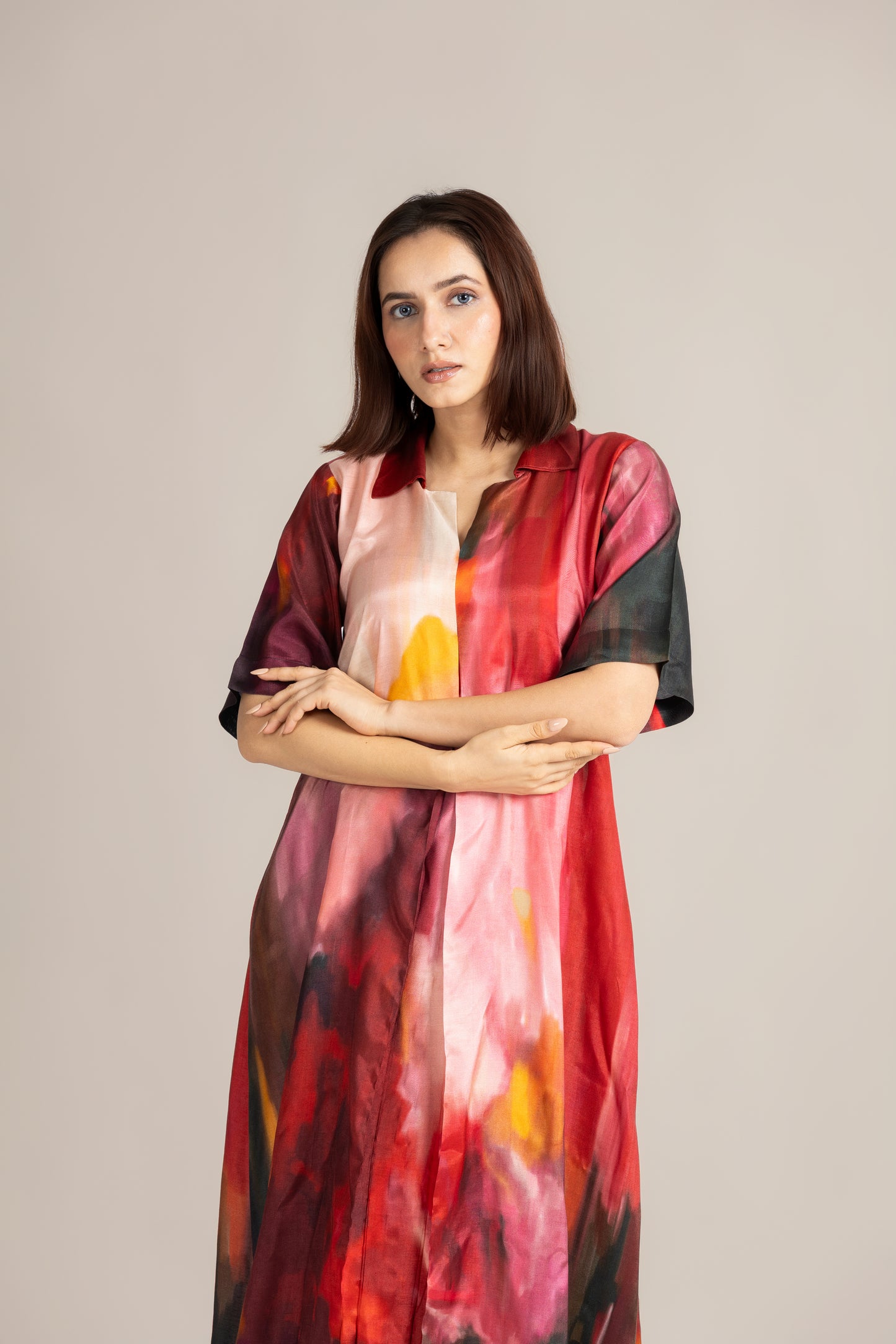 Woman wearing a colorful dress with abstract patterns on a plain background