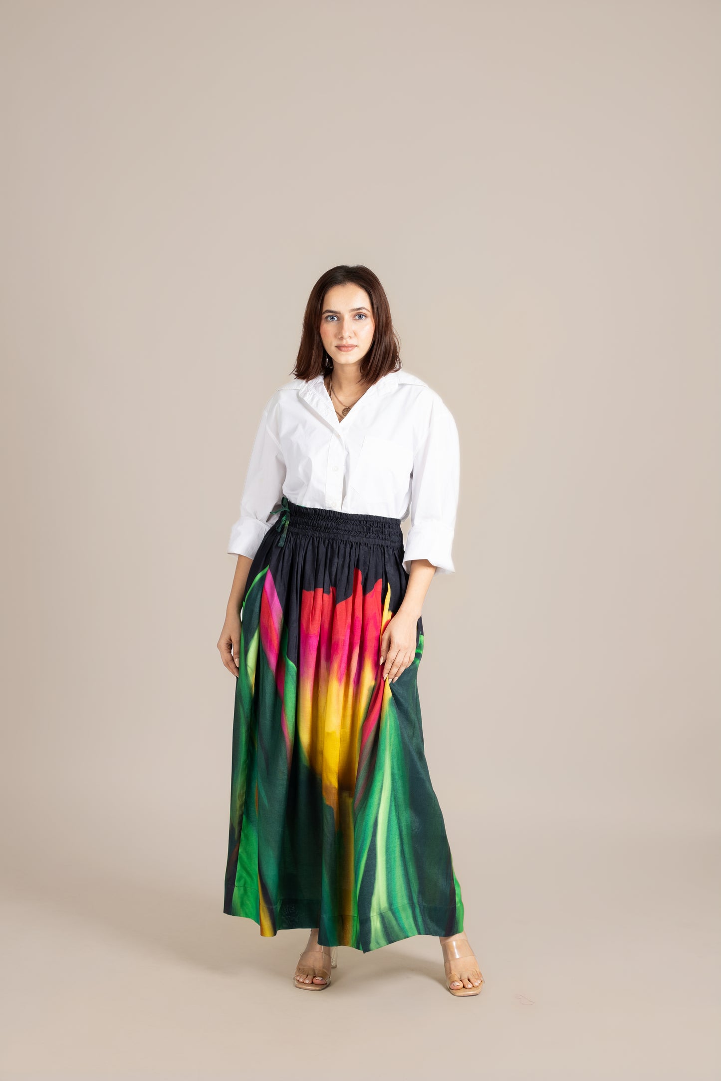 Woman wearing a white blouse and colorful skirt on a beige background
