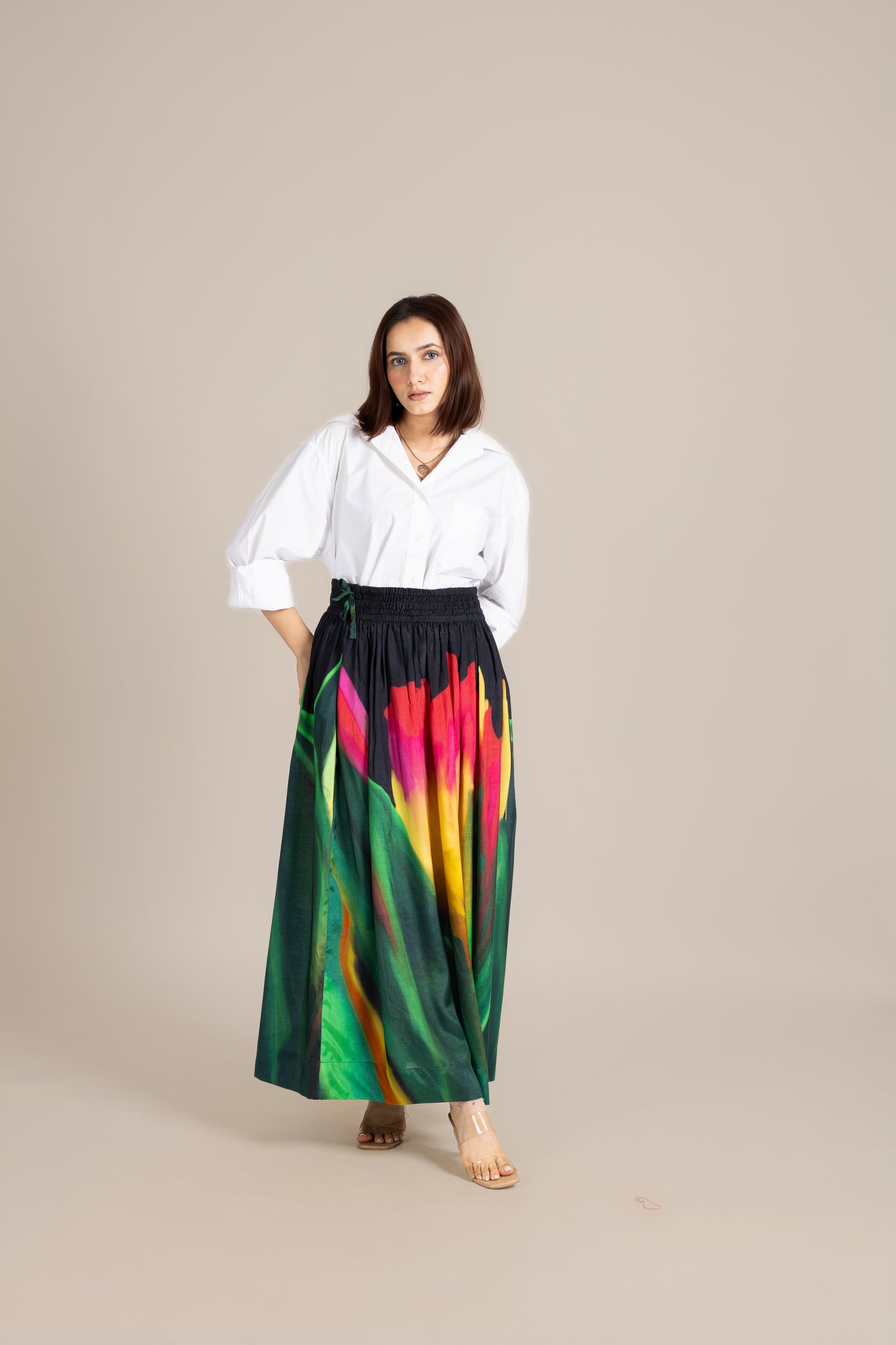 Woman wearing a white blouse and colorful tie-dye skirt on a beige background