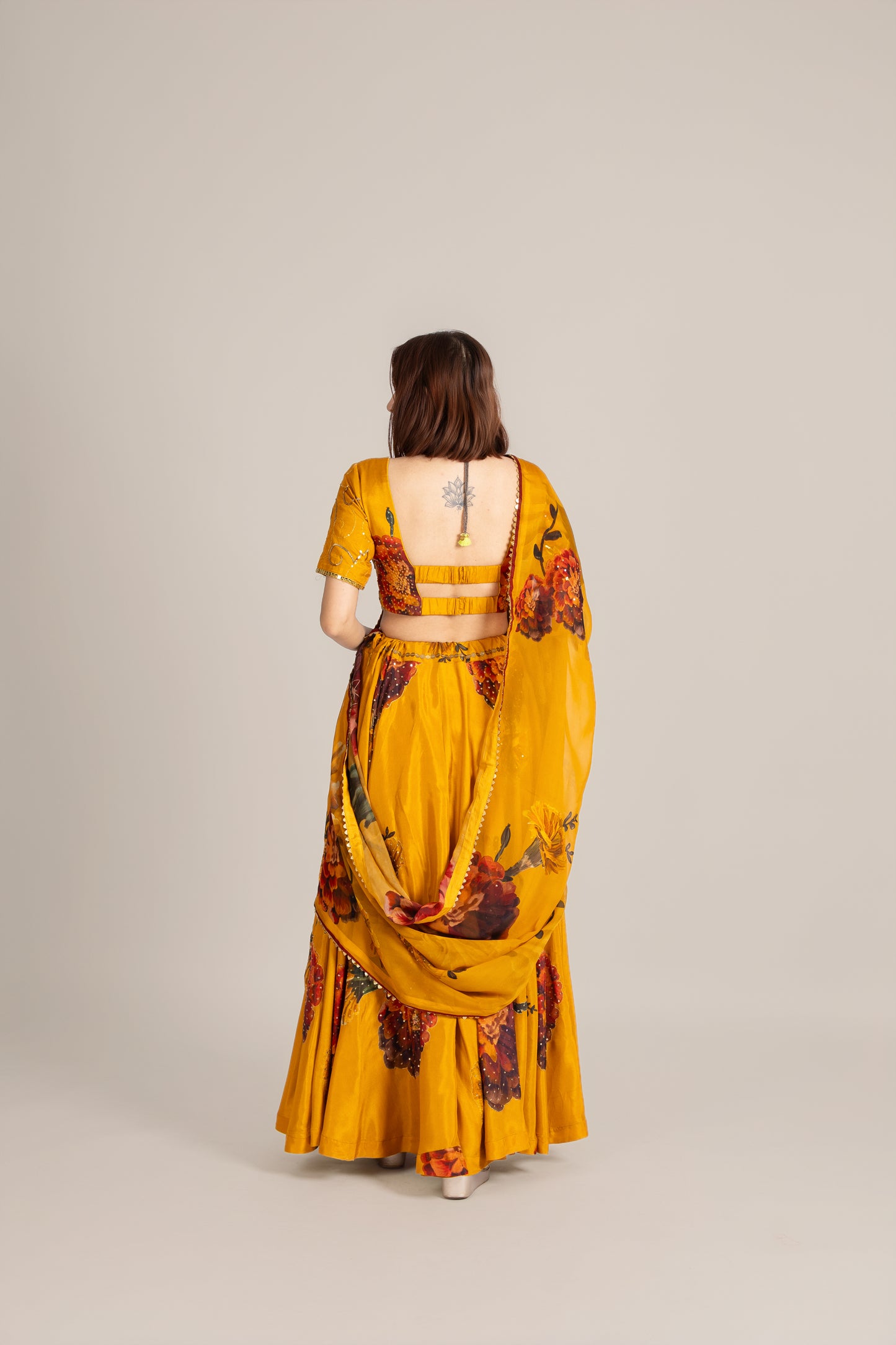 Woman wearing a mustard yellow floral outfit on a plain background