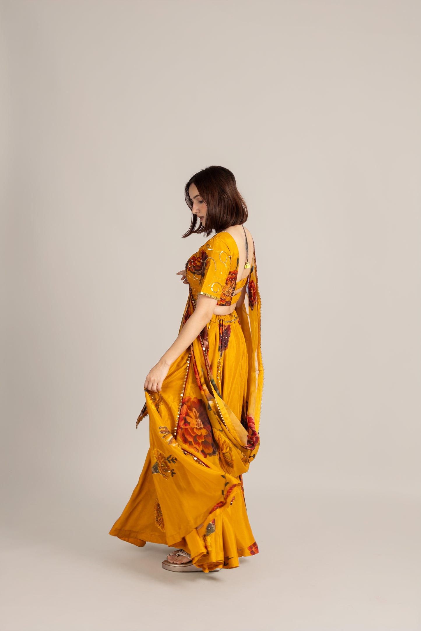 Woman wearing a yellow floral dress on a plain background