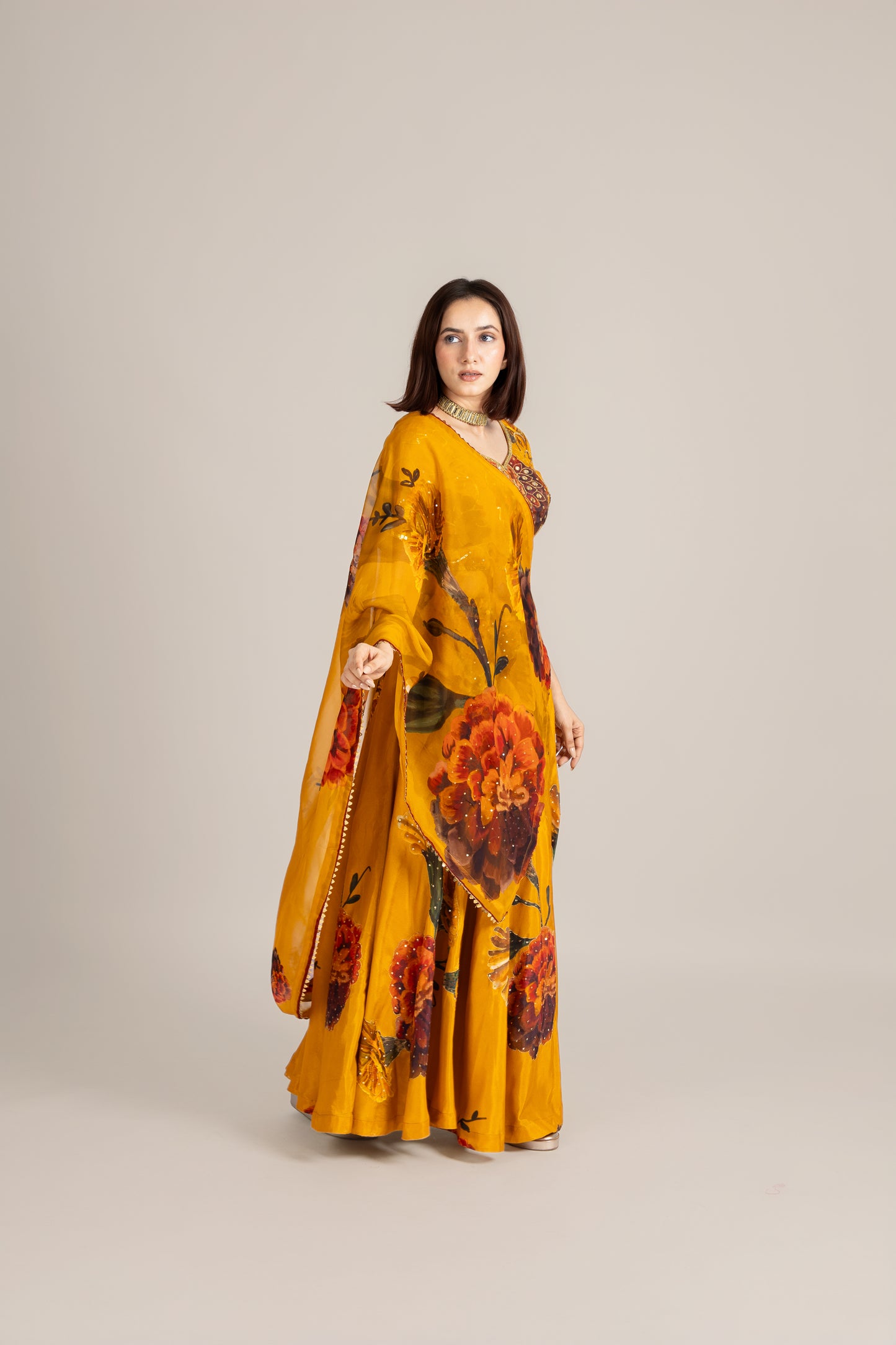 Woman wearing a mustard yellow floral dress on a beige background
