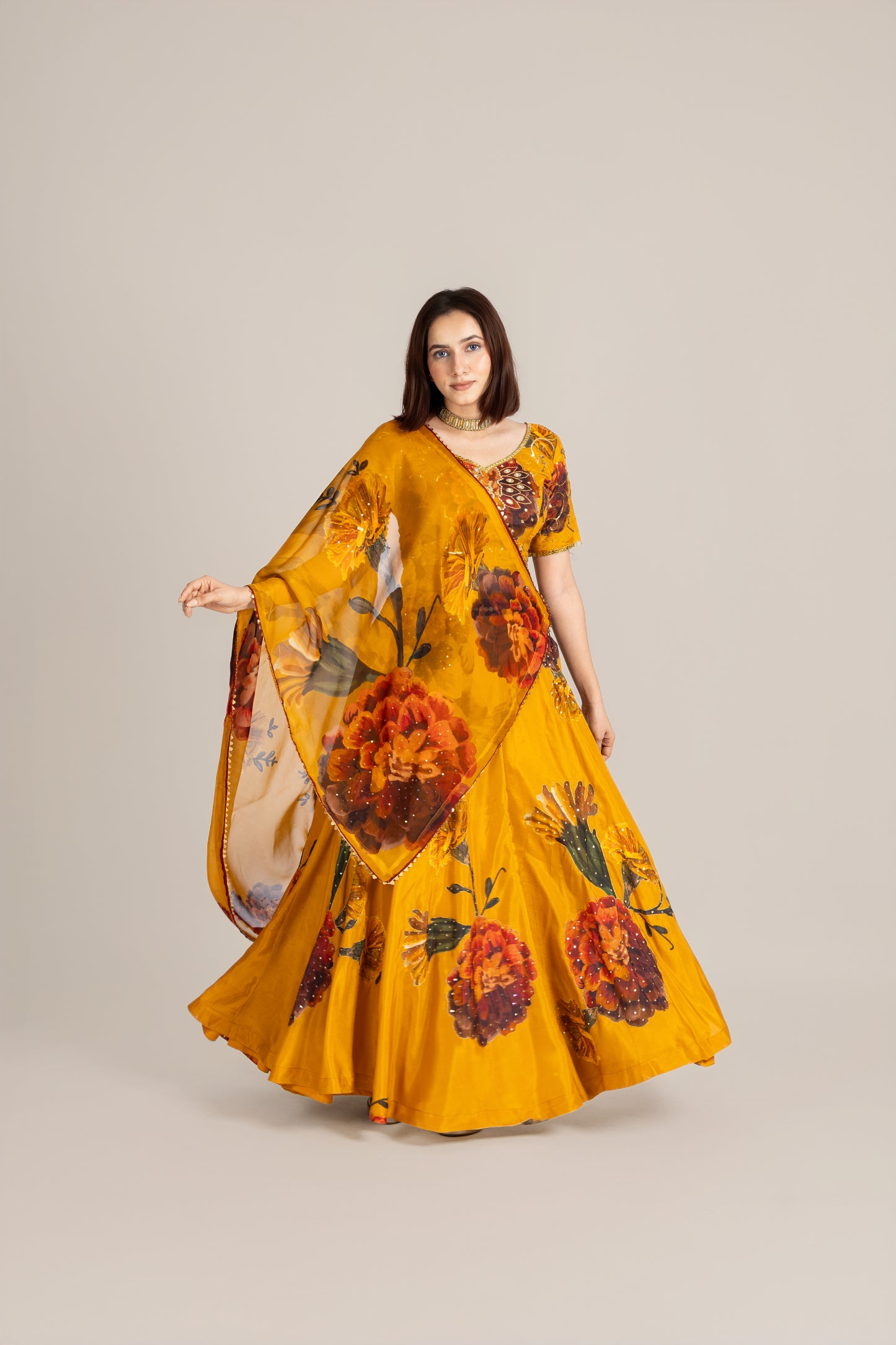 Woman wearing a yellow floral saree on a plain background
