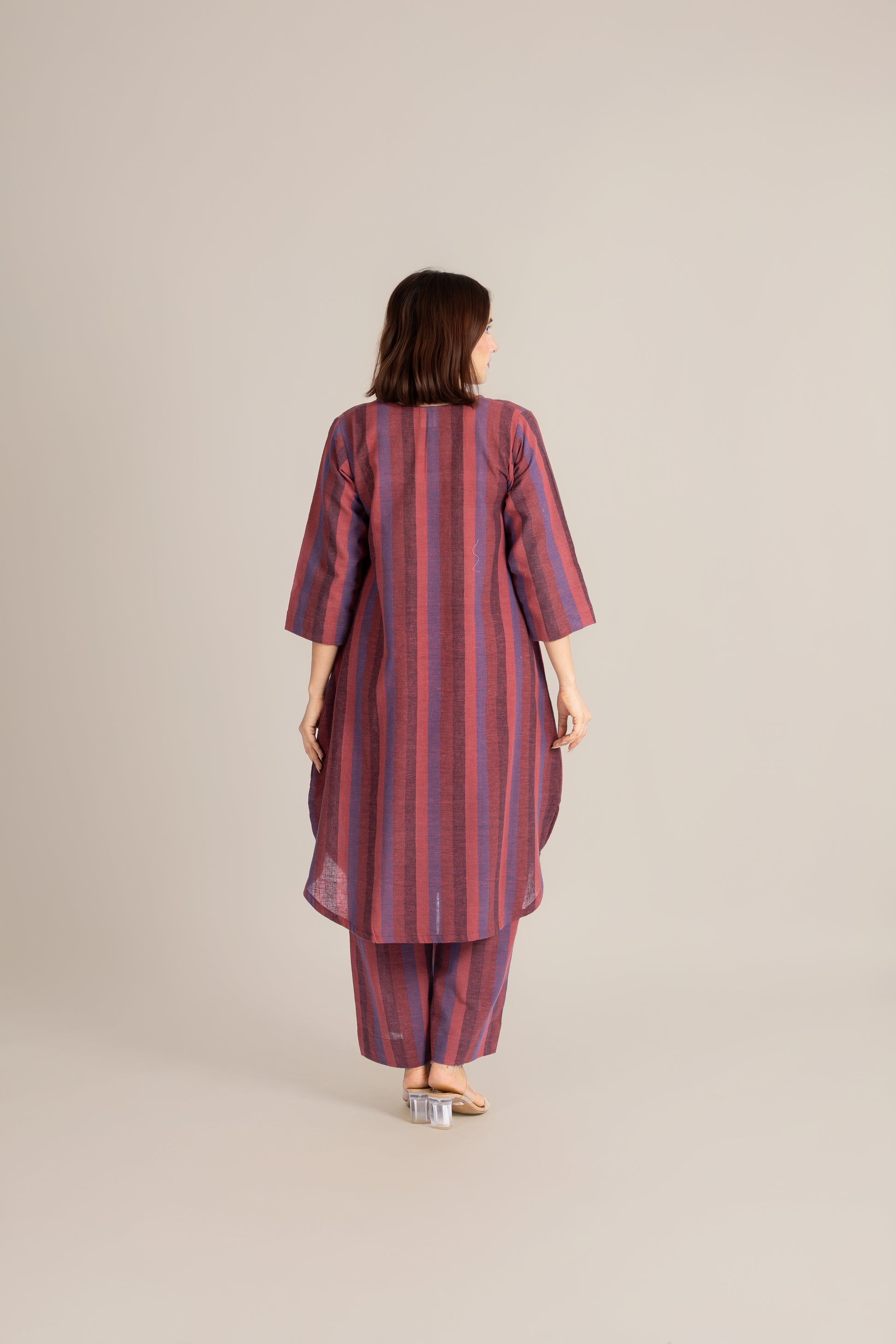 Woman wearing a red and purple striped outfit on a beige background