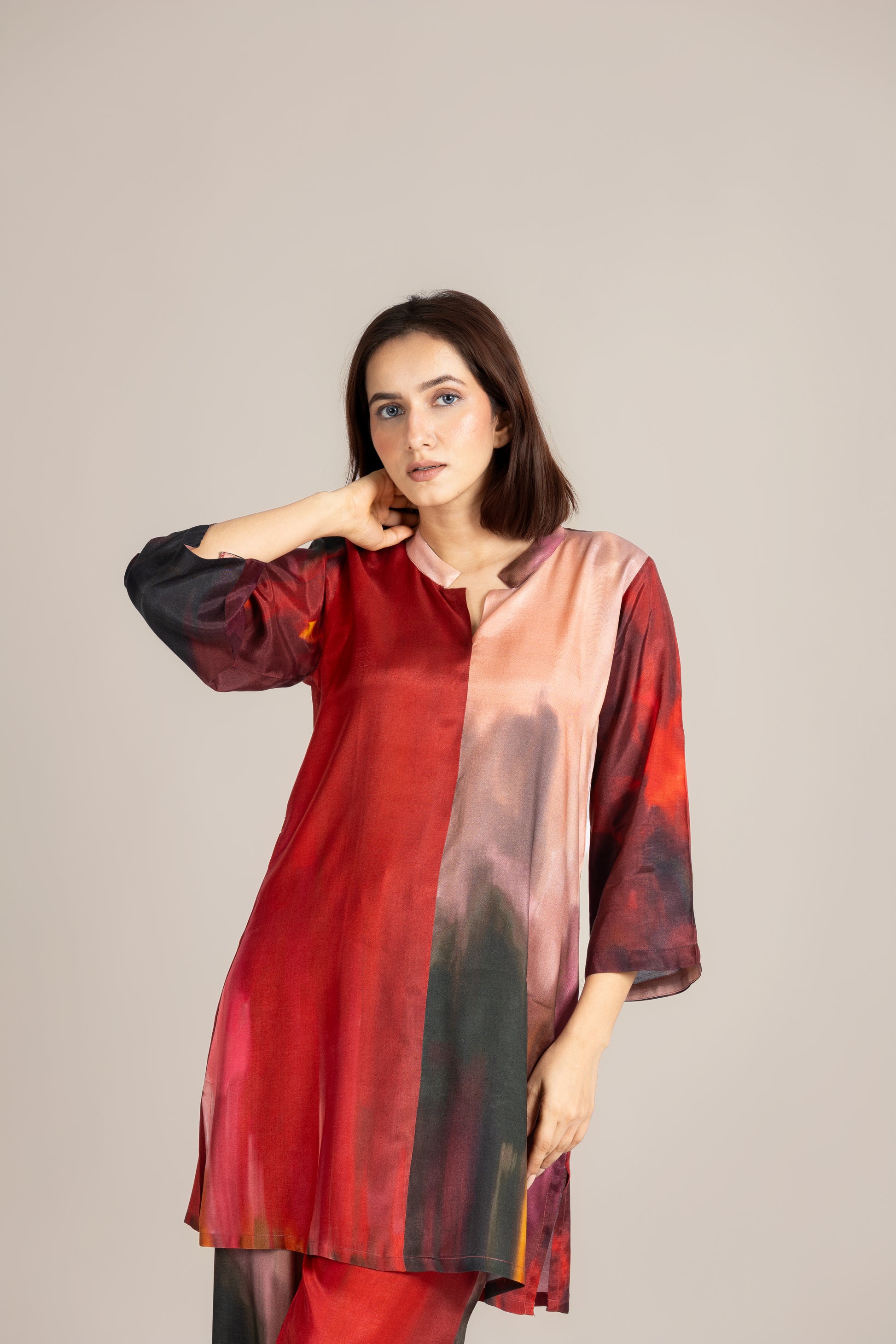 Woman wearing a red and black patterned kurta against a plain background