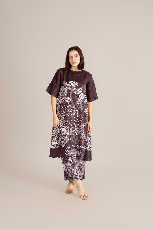 Woman wearing a dark purple dress with white patterns on a beige background
