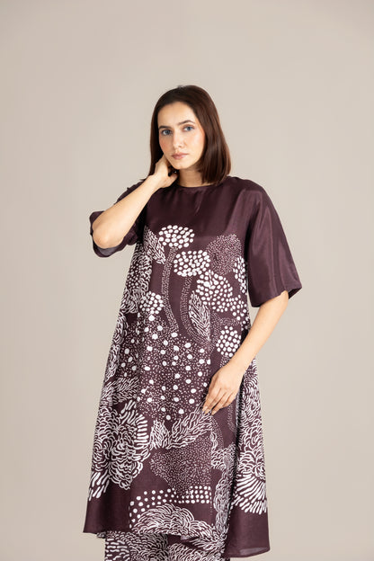 Woman wearing a dark brown dress with white floral pattern on a plain background