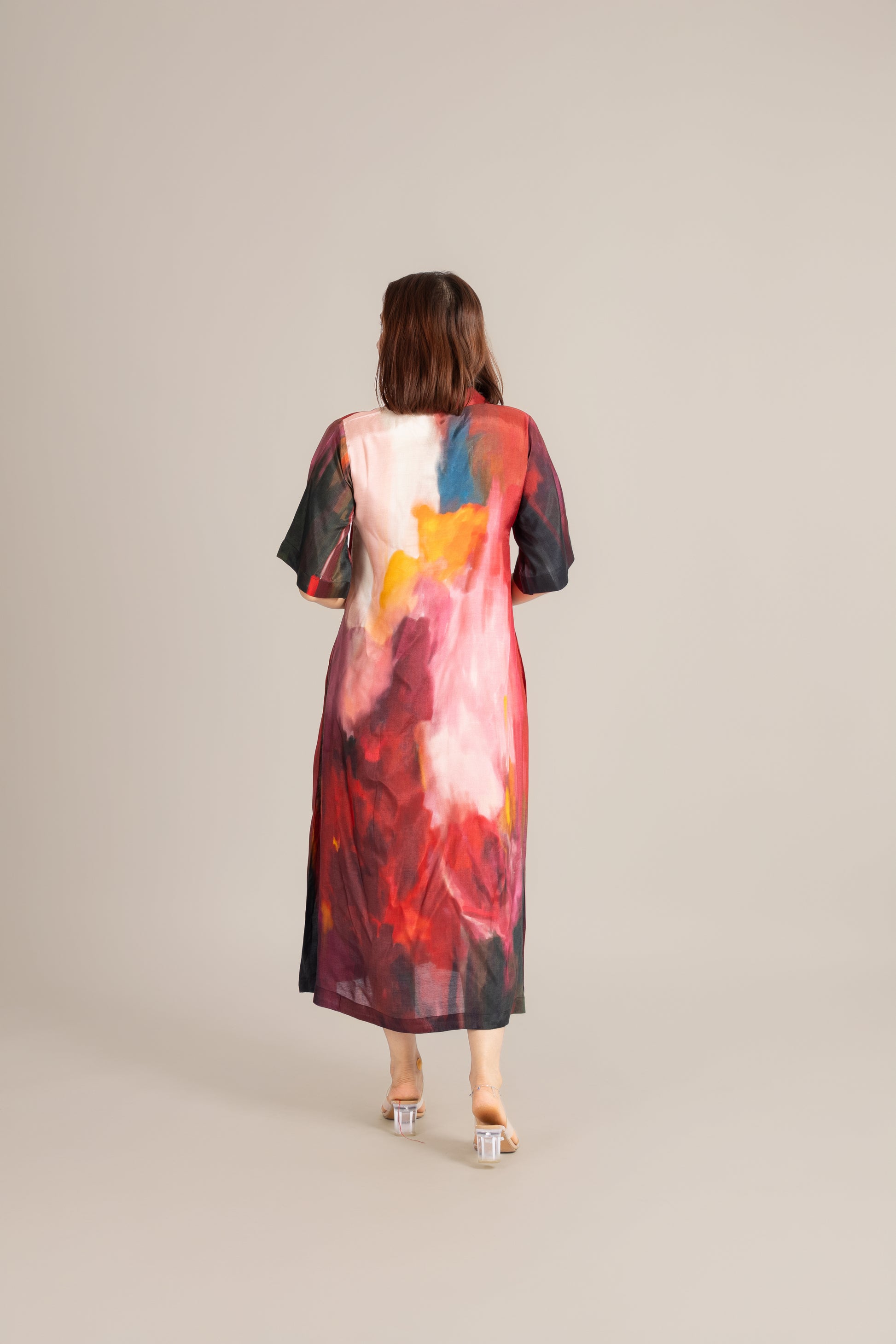 Woman wearing a colorful dress with abstract patterns on a plain background