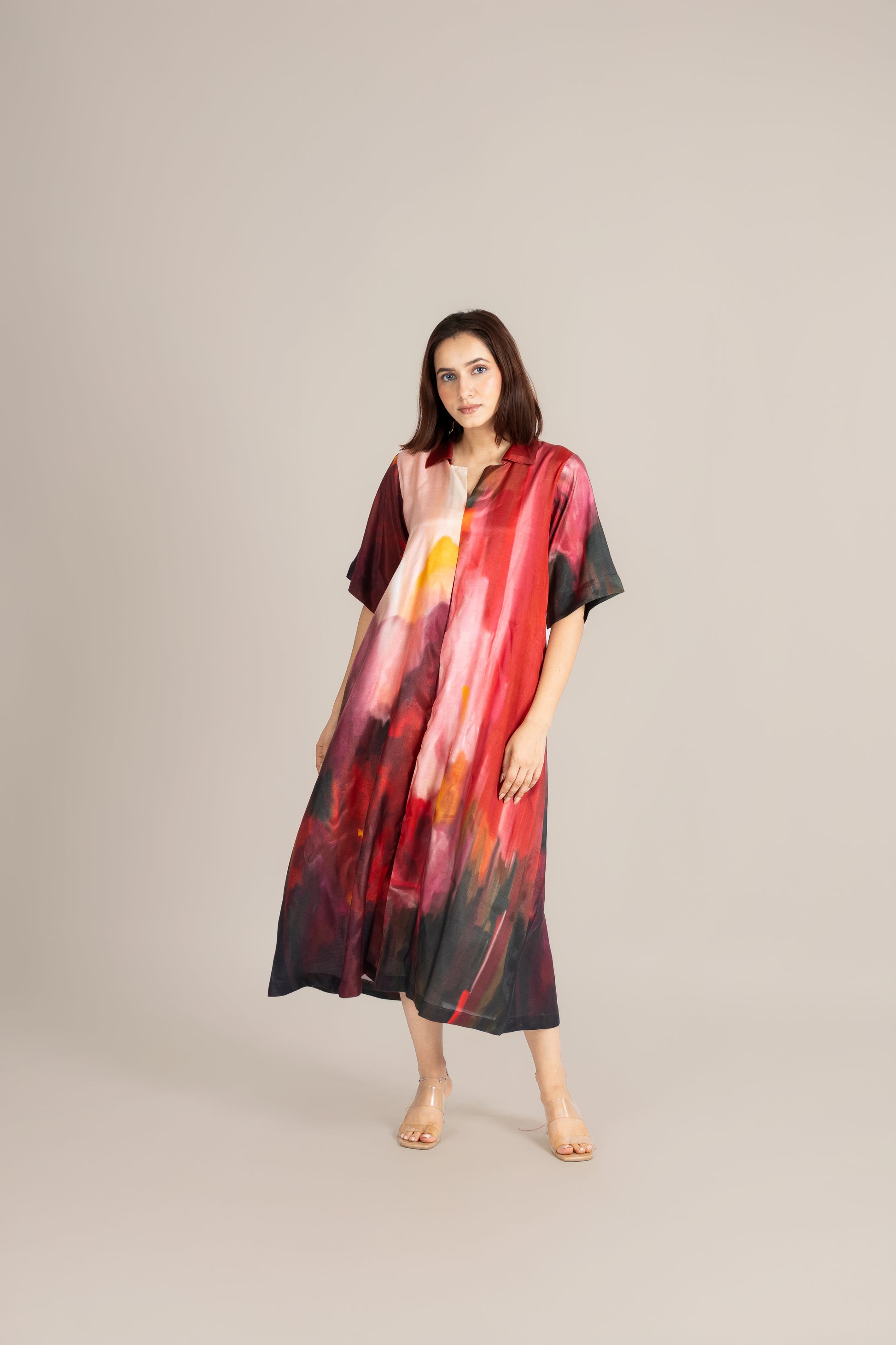 Woman wearing a colorful dress with abstract patterns on a plain background