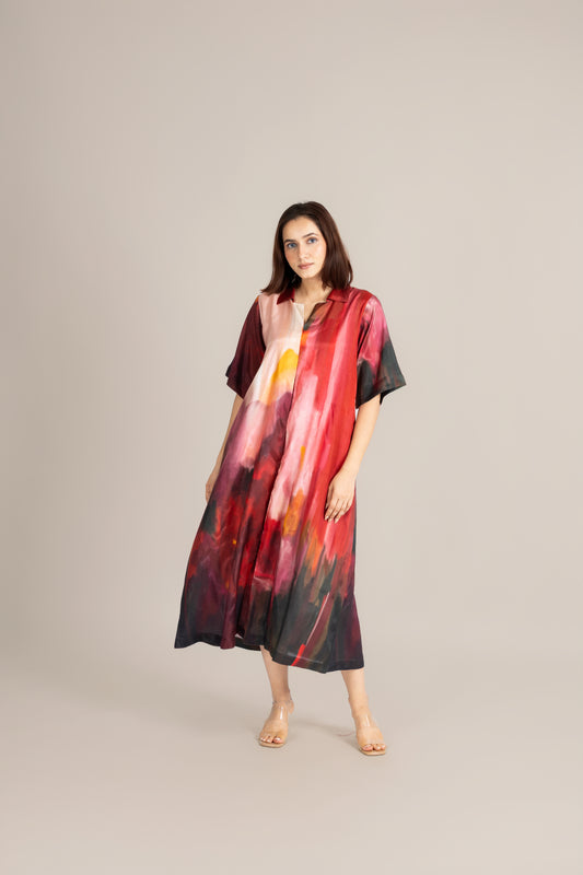 Woman wearing a colorful dress standing next to a wooden stool on a beige background