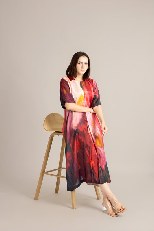 Woman wearing a colorful dress standing next to a wooden stool on a beige background