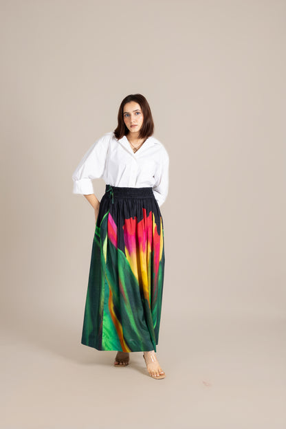 Woman wearing a white blouse and colorful tie-dye skirt on a beige background