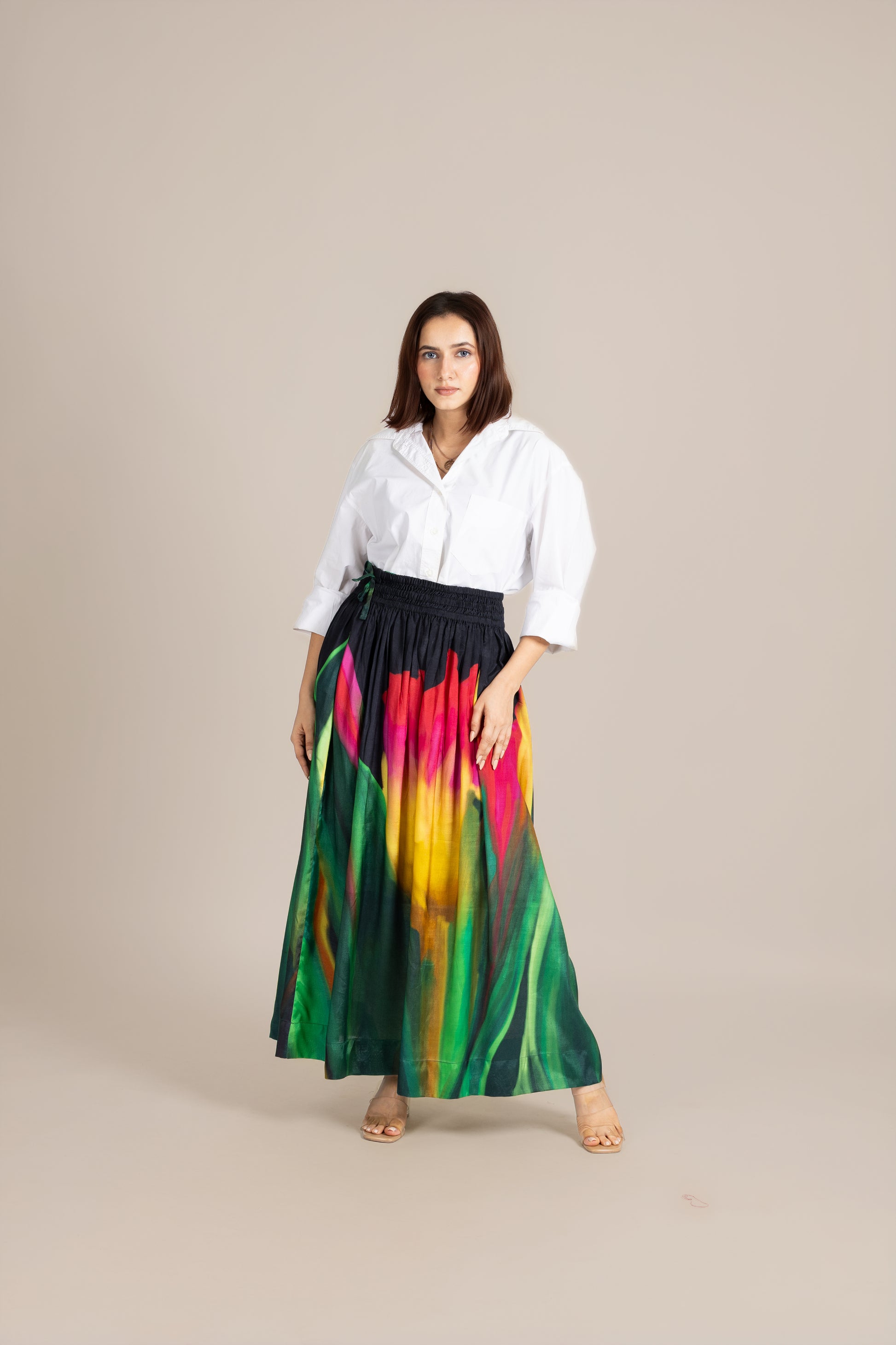 Woman wearing a white shirt and colorful skirt on a beige background