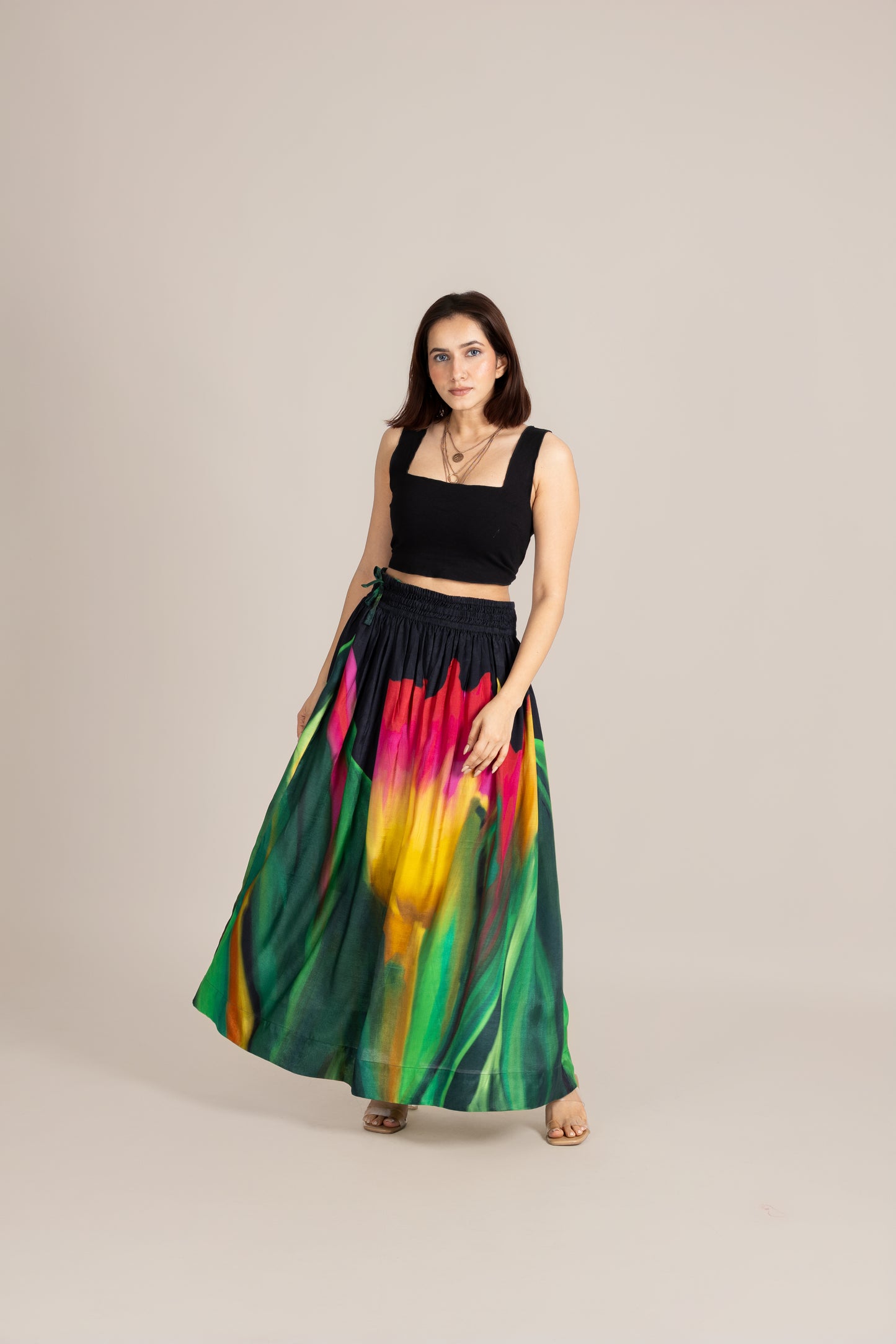 Woman wearing a black top and colorful skirt on a beige background
