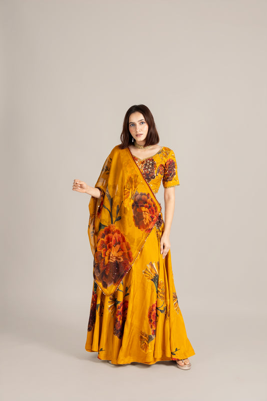 Woman wearing a yellow floral saree against a plain background