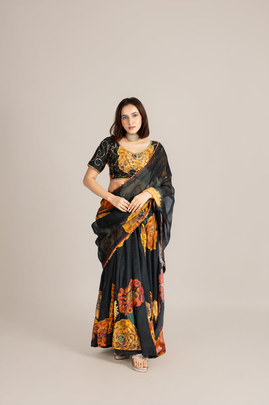 Woman wearing a black saree with floral patterns on a beige background