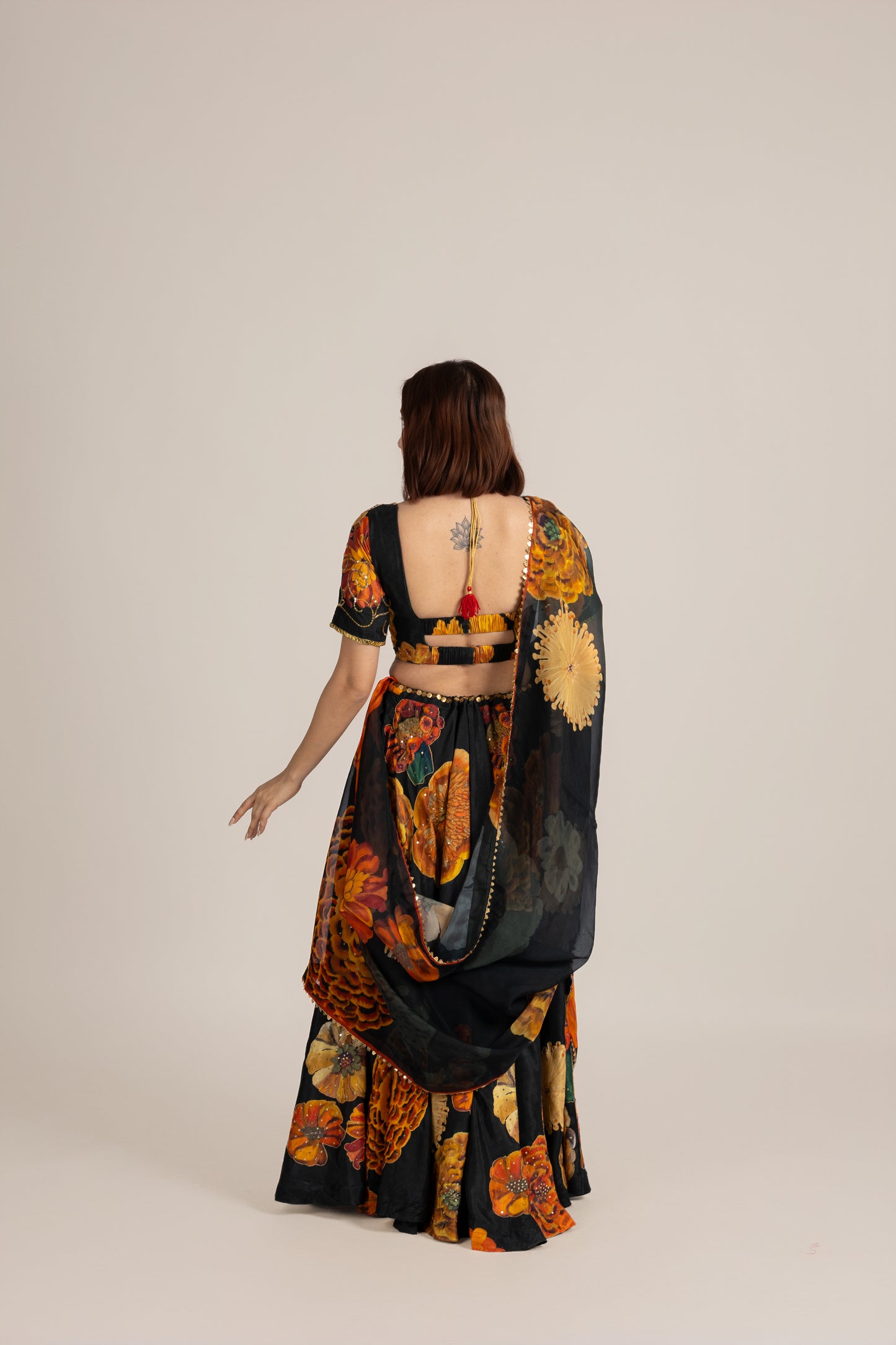 Woman wearing a colorful patterned saree with a plain background